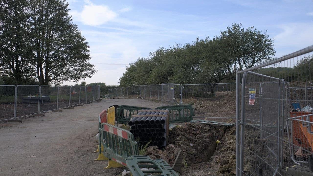 Construction barriers and fencing around a road work site; no people visible.