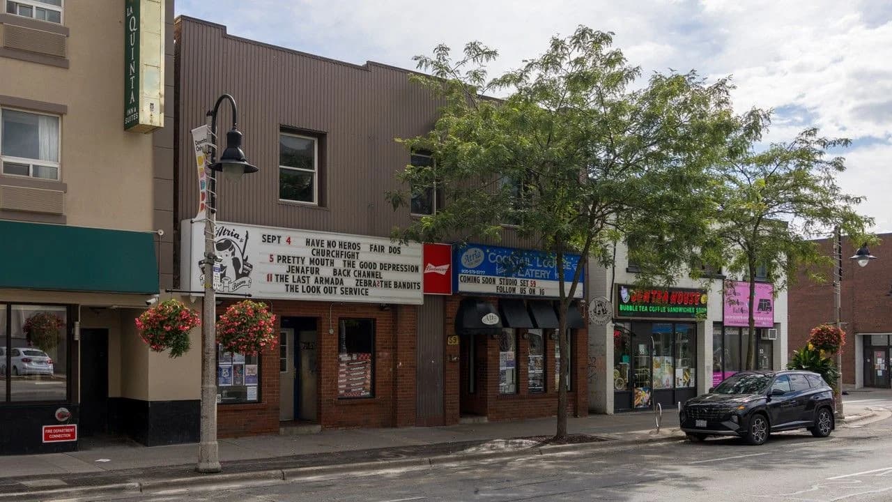 Downtown Oshawa storefronts on a quiet street with hanging flower baskets and shop signage; no people shown.
