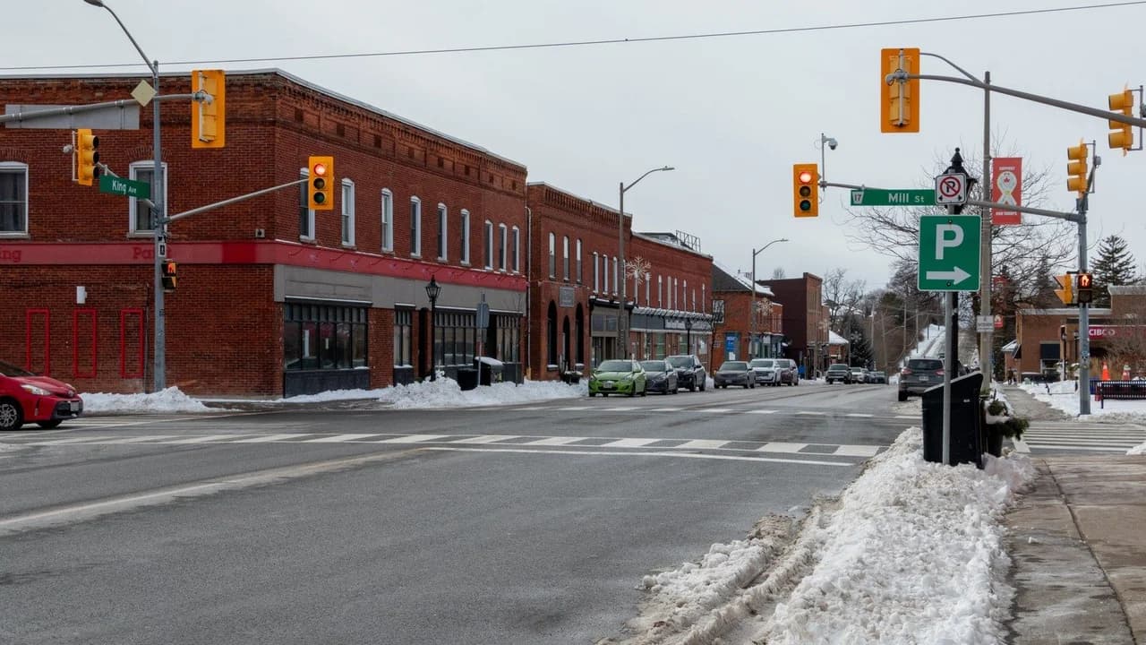 Downtown Newcastle, Ontario at the corner of King Avenue and Mill Street in winter; brick storefronts along a snow-cleared street, no people visible