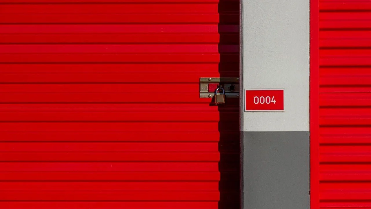 Red self-storage unit door secured with a padlock; no people visible