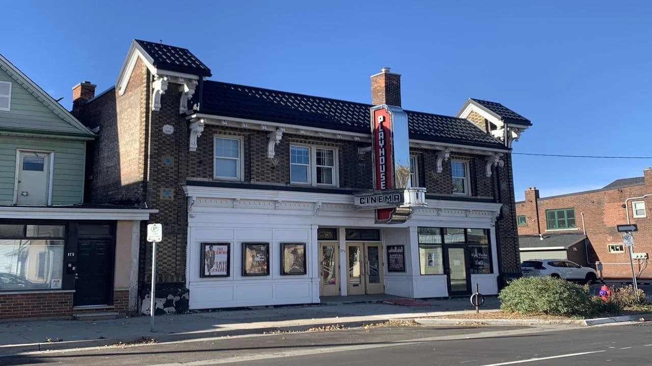 Daytime exterior of the Playhouse Cinema, a brick theatre building with a vertical blade sign and street-facing marquee; no people visible. Illustrative image, not the incident location.